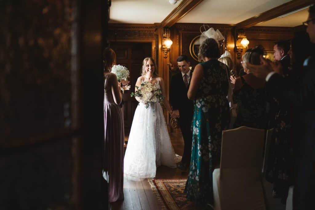 Bride and guests in a historic room during a wedding ceremony.