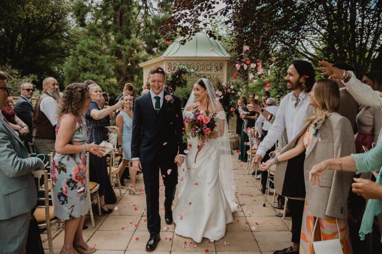 Wedding couple walking through guests in a garden setting.