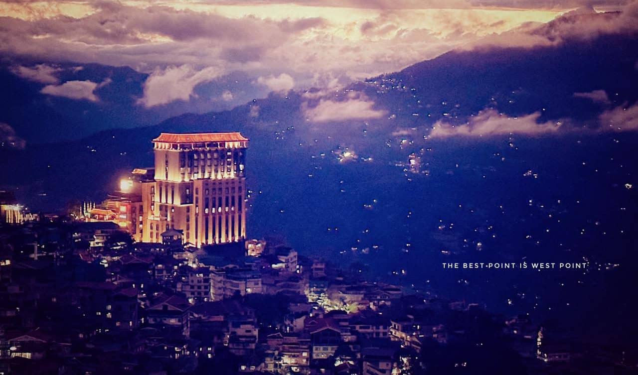 Elegant cityscape at dusk with mountain backdrop, highlighting urban architecture and scenic views.
