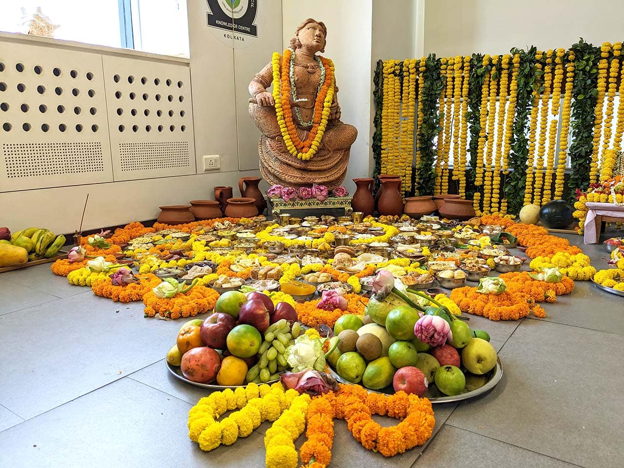 Colorful religious altar with flowers, fruits, and traditional decorations for Hindu worship.