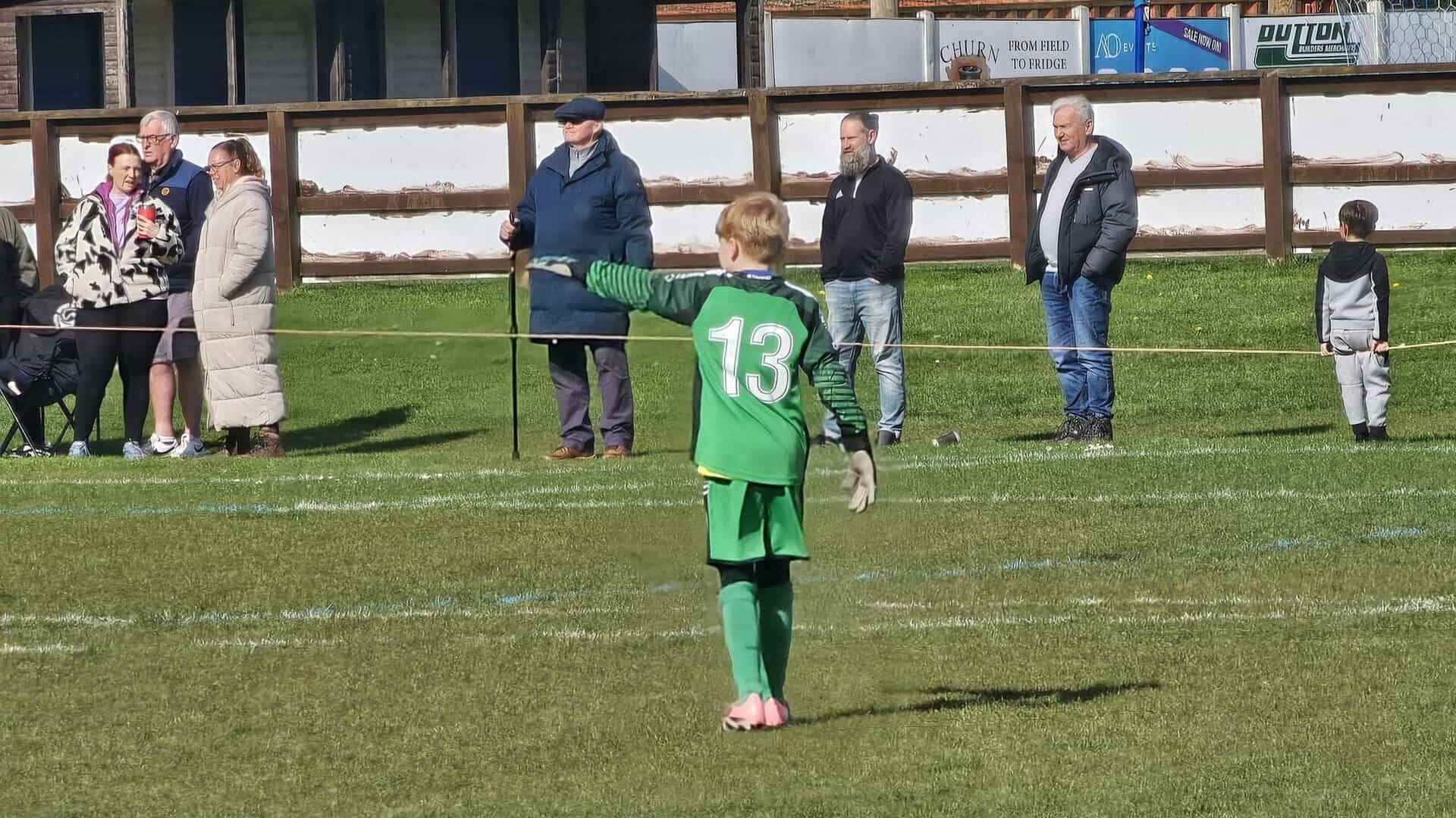 Sandbach United youth football player wearing green kit with number 13 on the field.