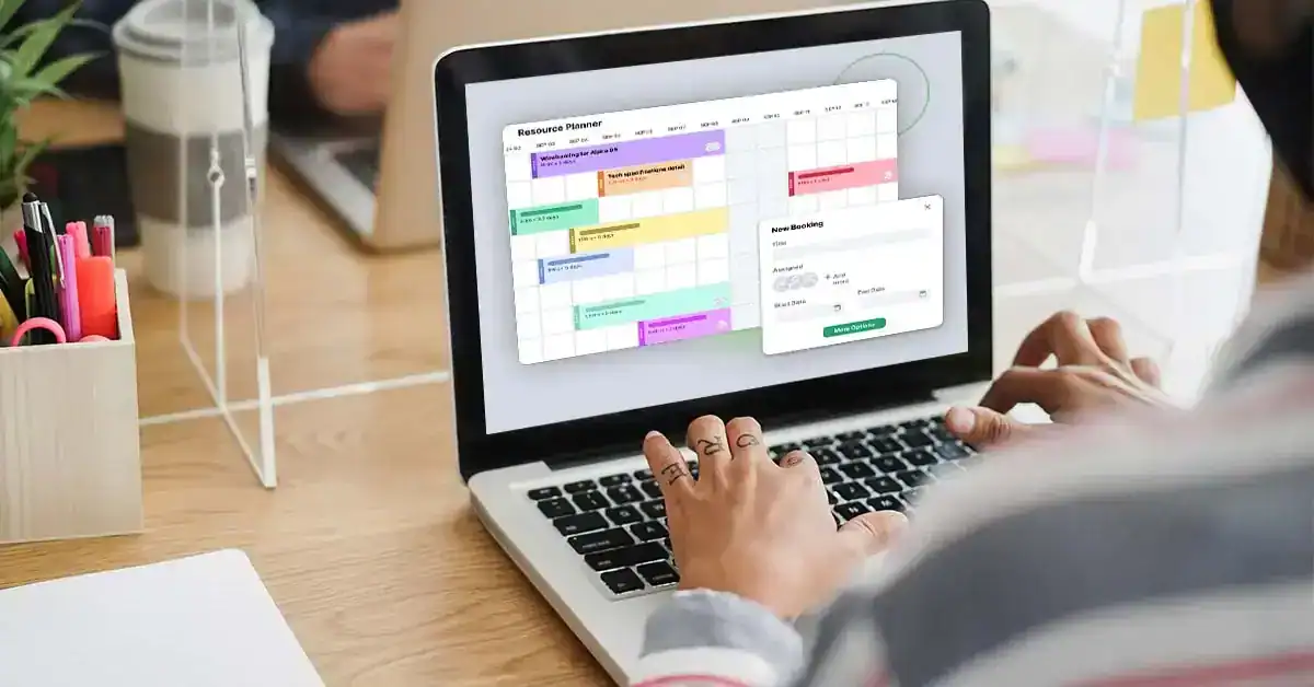 Person using project management software on a laptop in a modern office setting.