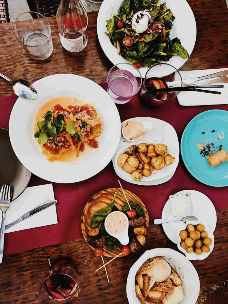 Tisch in einem Restaurant mit stilvoll angerichteten Speisen und Getränken – Szene aus einem gastronomischen Betrieb mit lebendiger Geräuschkulisse.