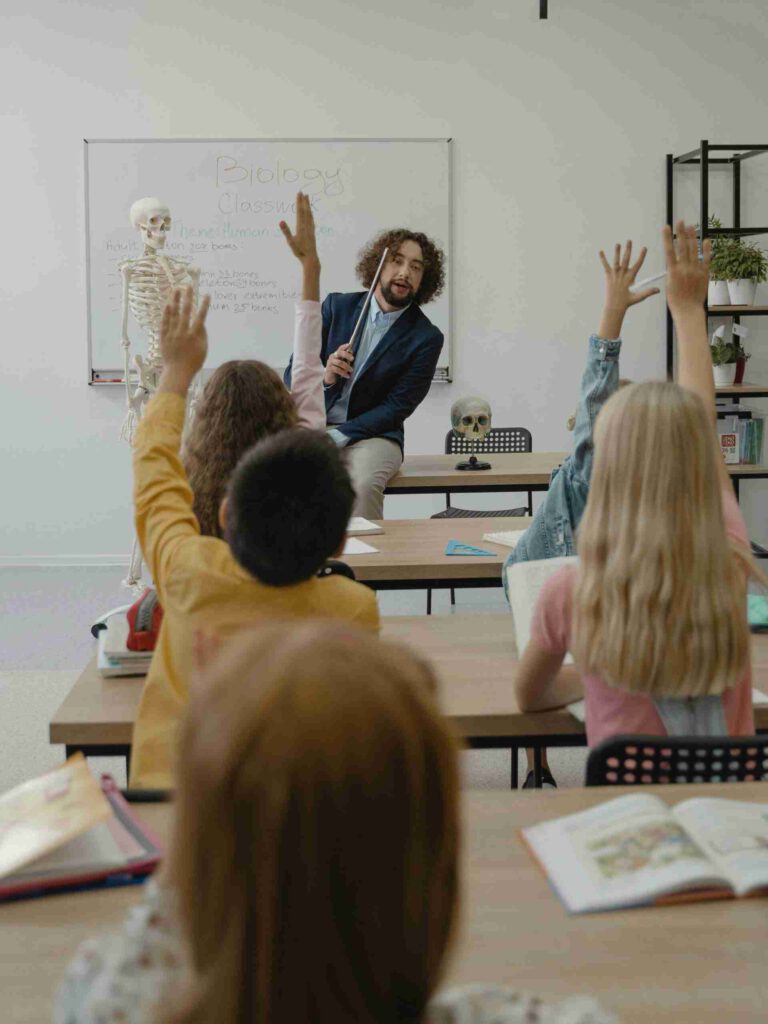 Grundschulklasse mit Lehrer und Kindern beim Unterricht – akustisch sensible Umgebung mit hoher Geräuschbelastung in Bildungsstätten.