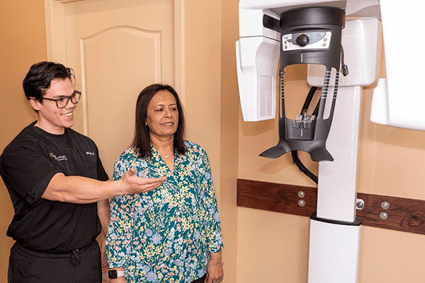A dental assistant shows a patient a Panoramic X-ray machine