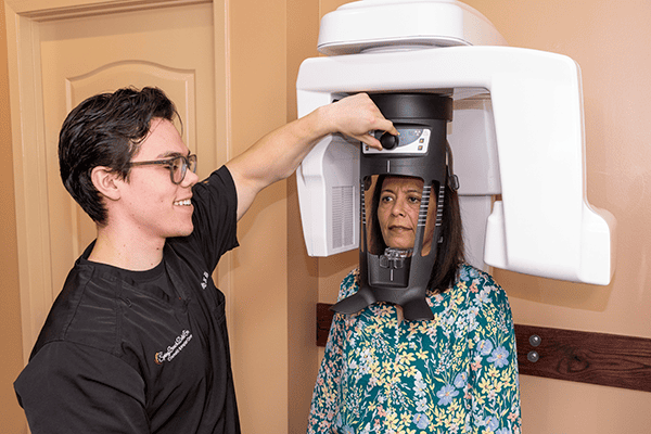 A dental assistant initiates a 3D scan with a patient