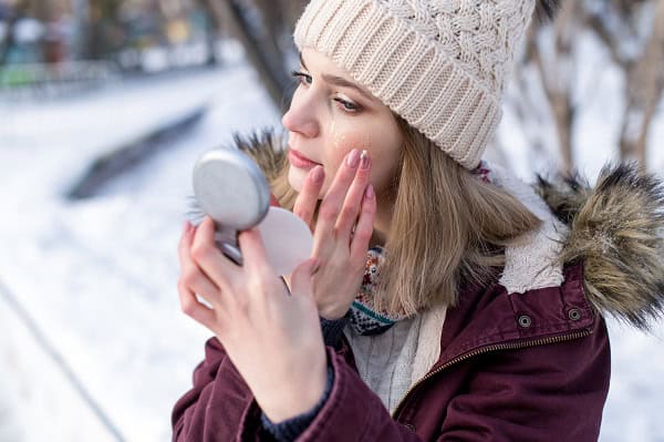 Donna controlla i segni dell'inverno sulla sua pelle allo specchio.