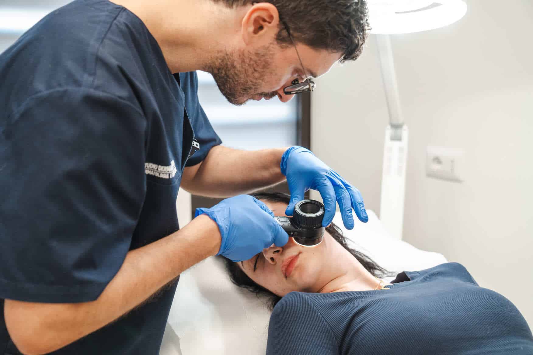Diagnosi dermatologica con dermatoscopio su paziente donna in studio.