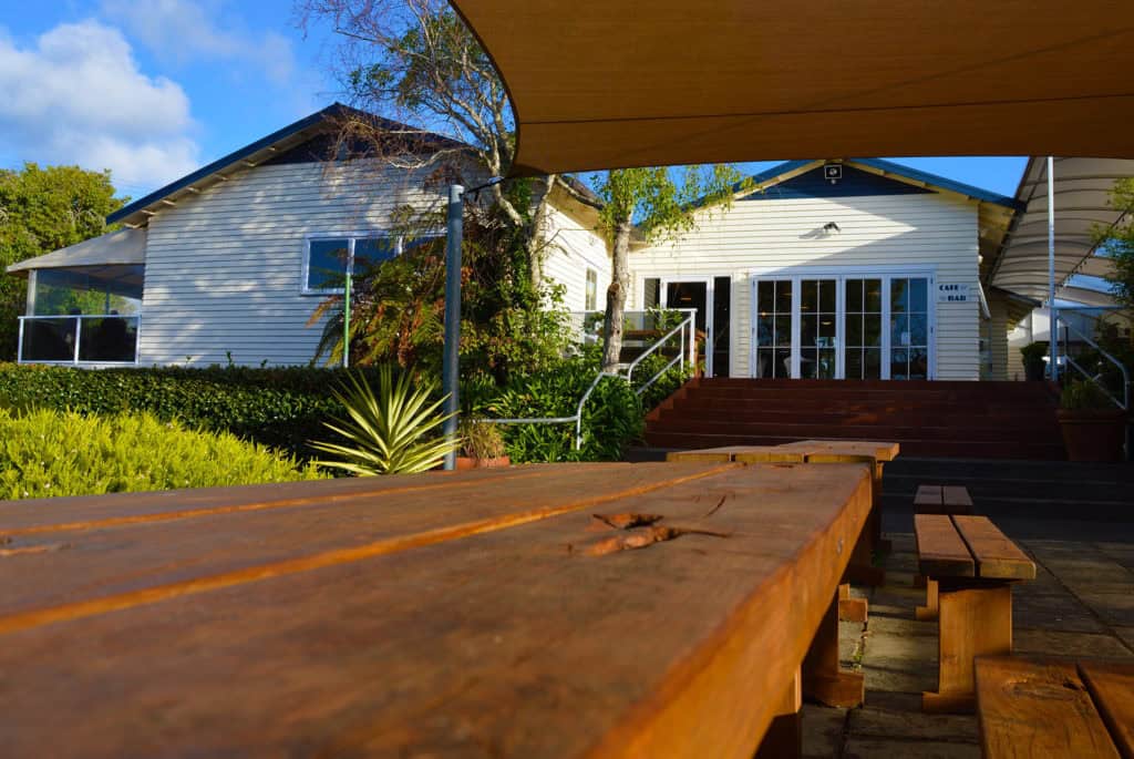 Seaside outdoor patio at Stumble Inn with wooden benches and lush garden setting in New Zealand.