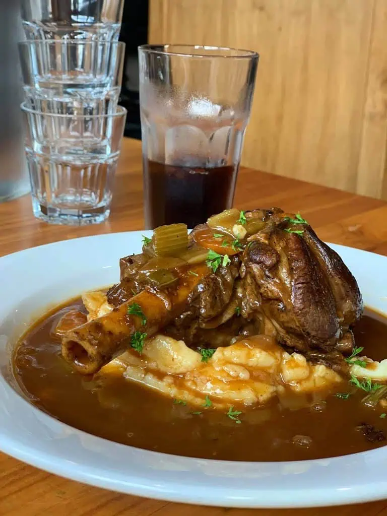 Juicy braised lamb shank with mashed potatoes and rich gravy at Stumble Inn NZ.