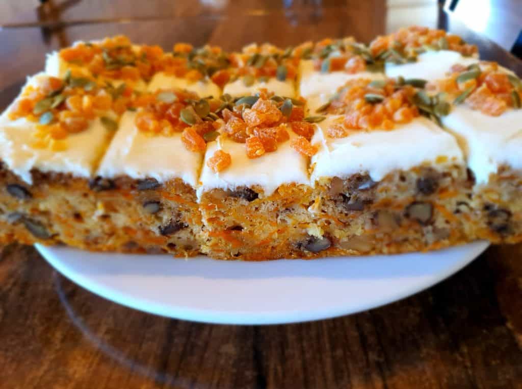 Creamy carrot cake with cream cheese frosting topped with mixed seeds and candied ginger. Delicious dessert at Stumble Inn.
