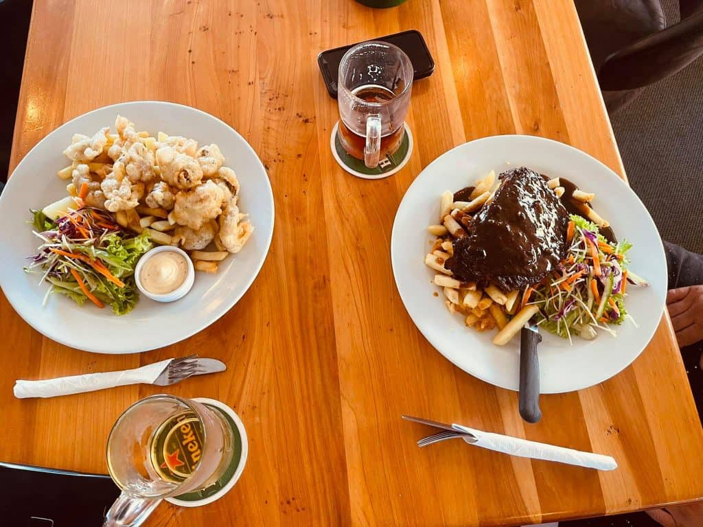 Crispy fried chicken with salad and dipping sauce, served with beer at Stumble Inn, NZ.