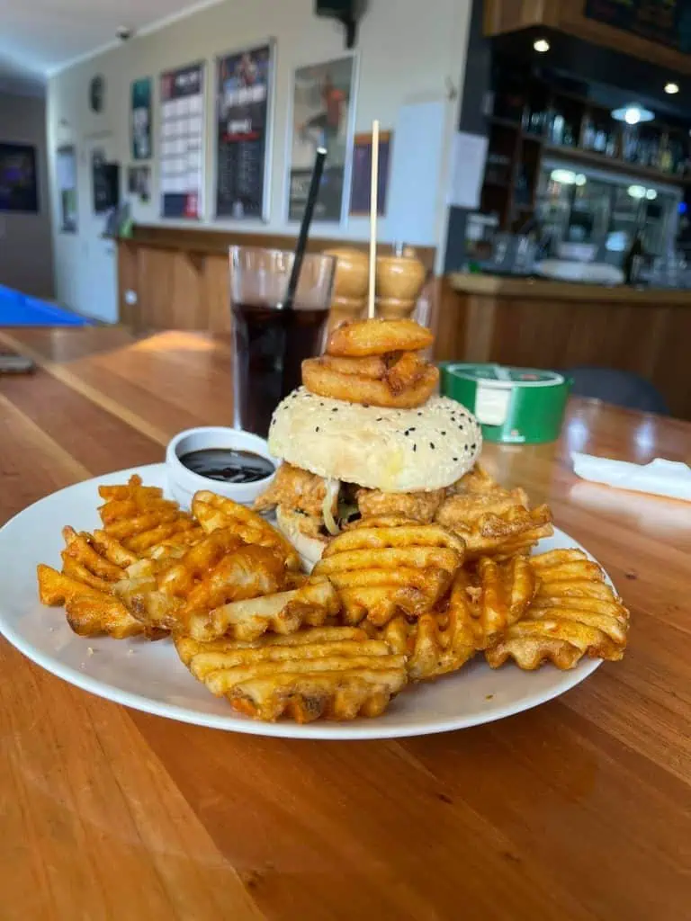 Classic pub-style burger with crispy waffle fries and onion rings at Stumble Inn New Zealand.