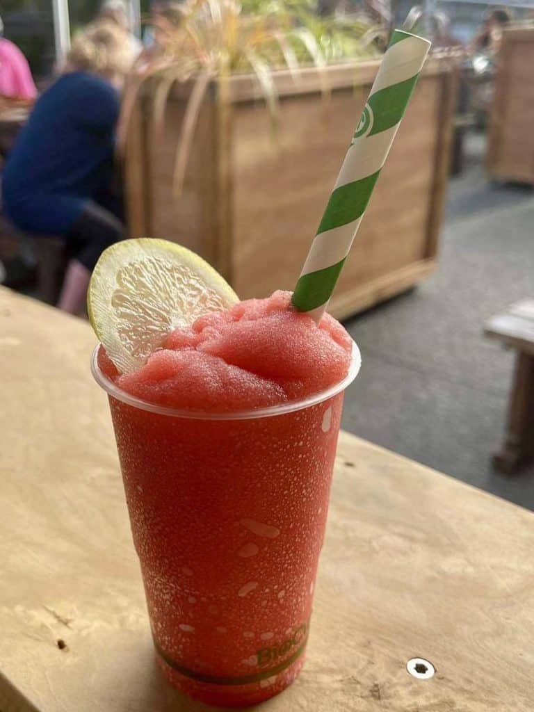 Refreshing watermelon summer drink with lemon slice and striped straw at Stumble Inn, outdoor dining in New Zealand.