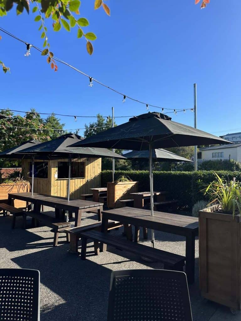 Outdoor pub patio with large umbrellas at Stumble Inn in New Zealand, perfect for socialising.