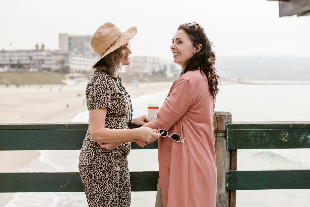 two women discussing perimenopause by the beach.
