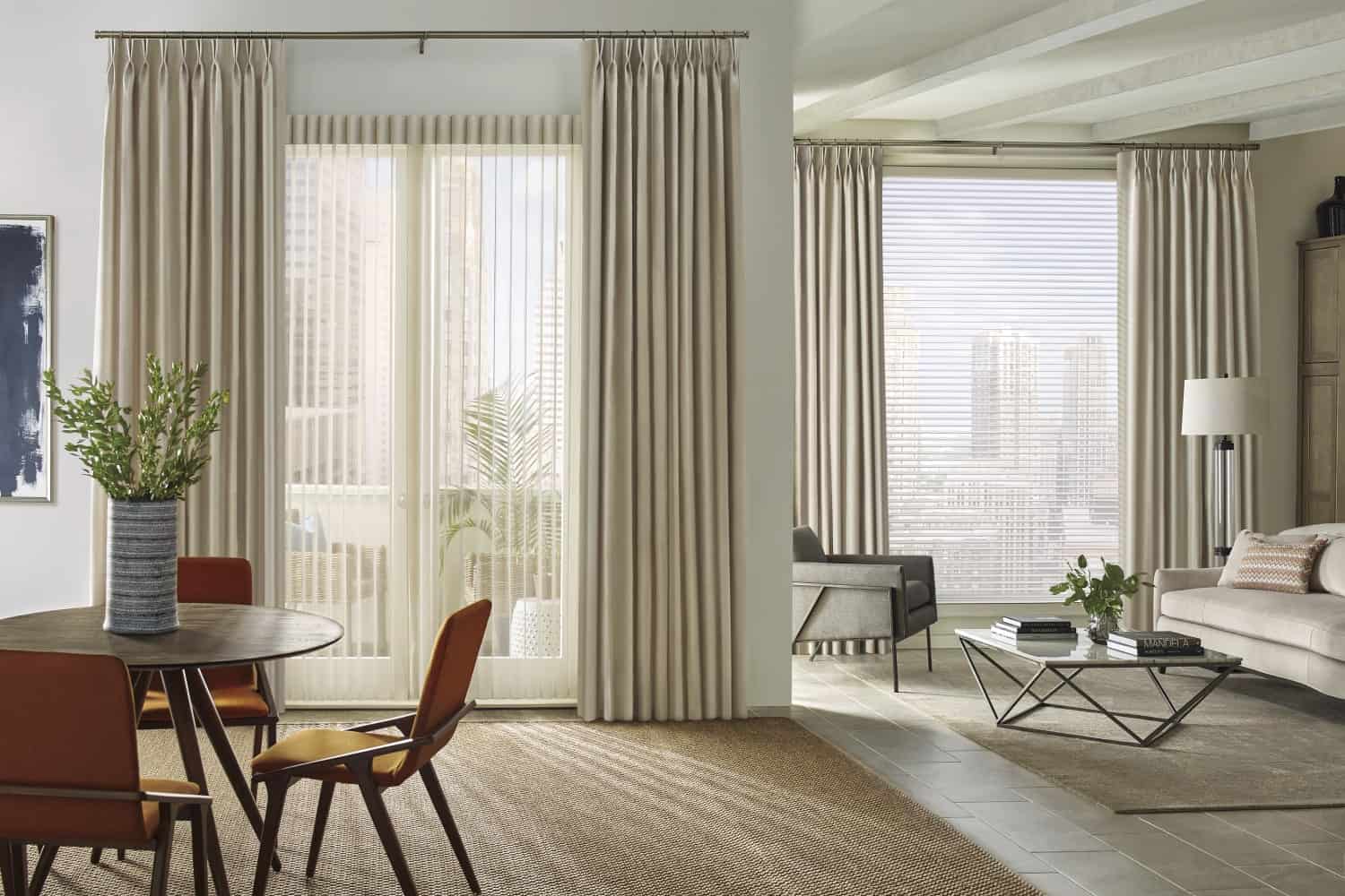 Bright living room with large windows, beige curtains, and contemporary furniture including a sofa, armchair, and coffee table.