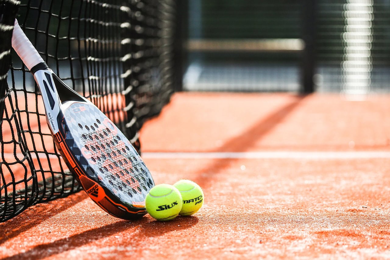 Padel racket on a padel court with tennis balls