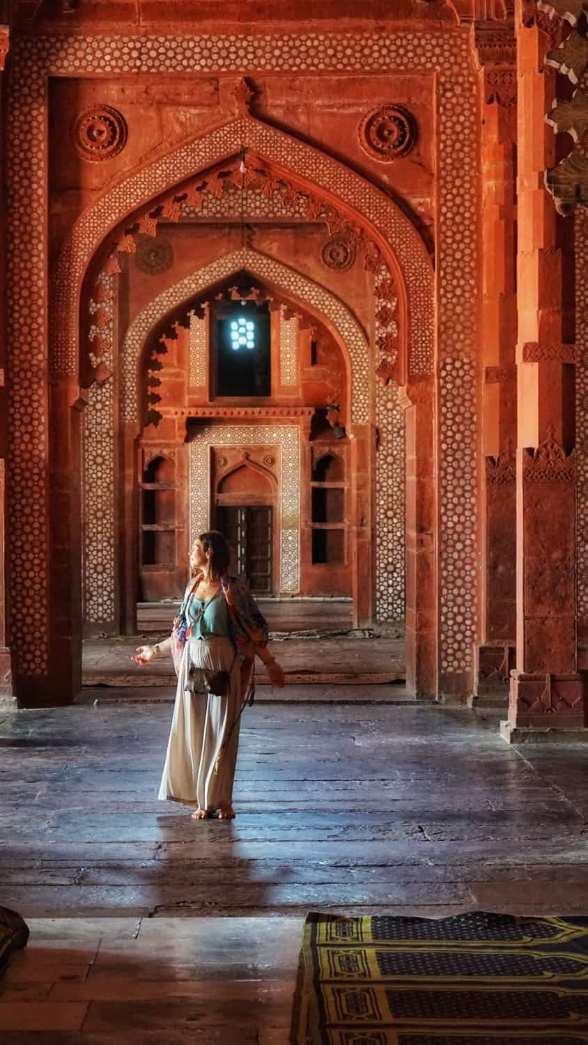 Donna in abiti tradizionali in un tempio marocchino con archi decorati.
