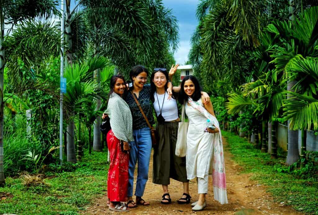 Gruppo di donne sorridenti in un giardino tropicale, viaggio e benessere.