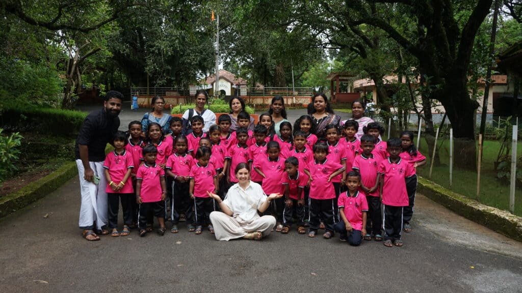 Gruppo di bambini e insegnanti durante attività di meditazione all'aperto.