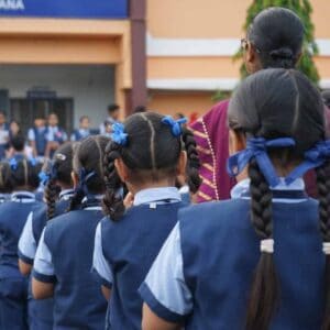 Immagine di bambini in uniforme scolastica durante attivit&agrave; di yoga all'aperto.