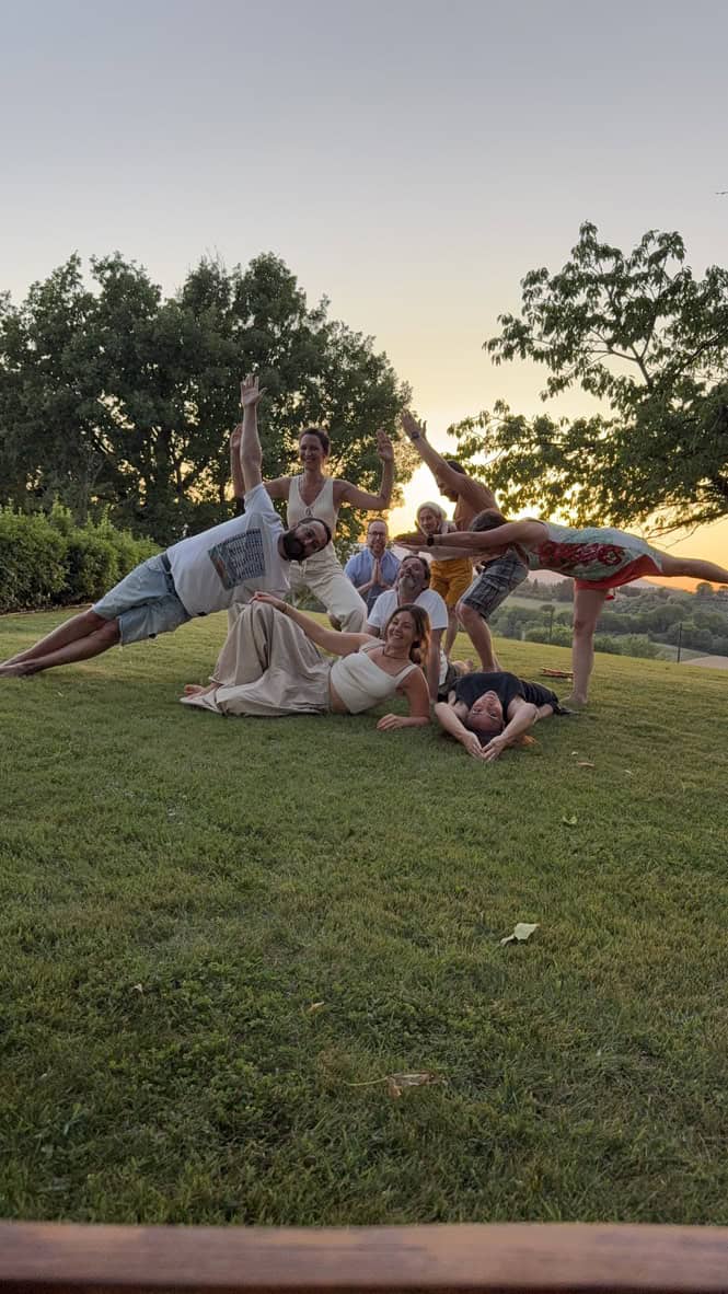 Gruppo di persone che praticano yoga in natura al tramonto.