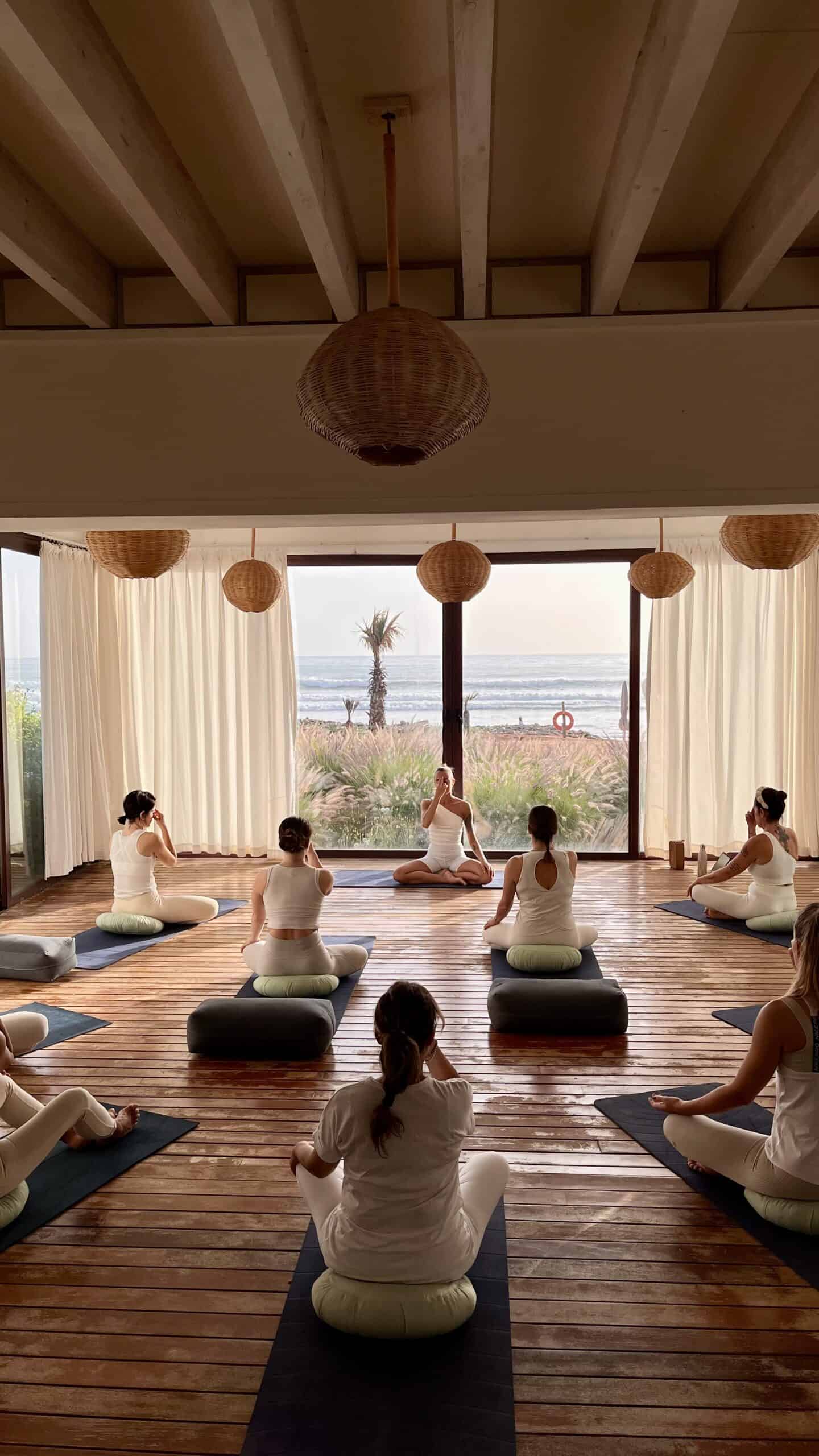 Gruppo di persone che praticano yoga in una sala con vista sul mare.