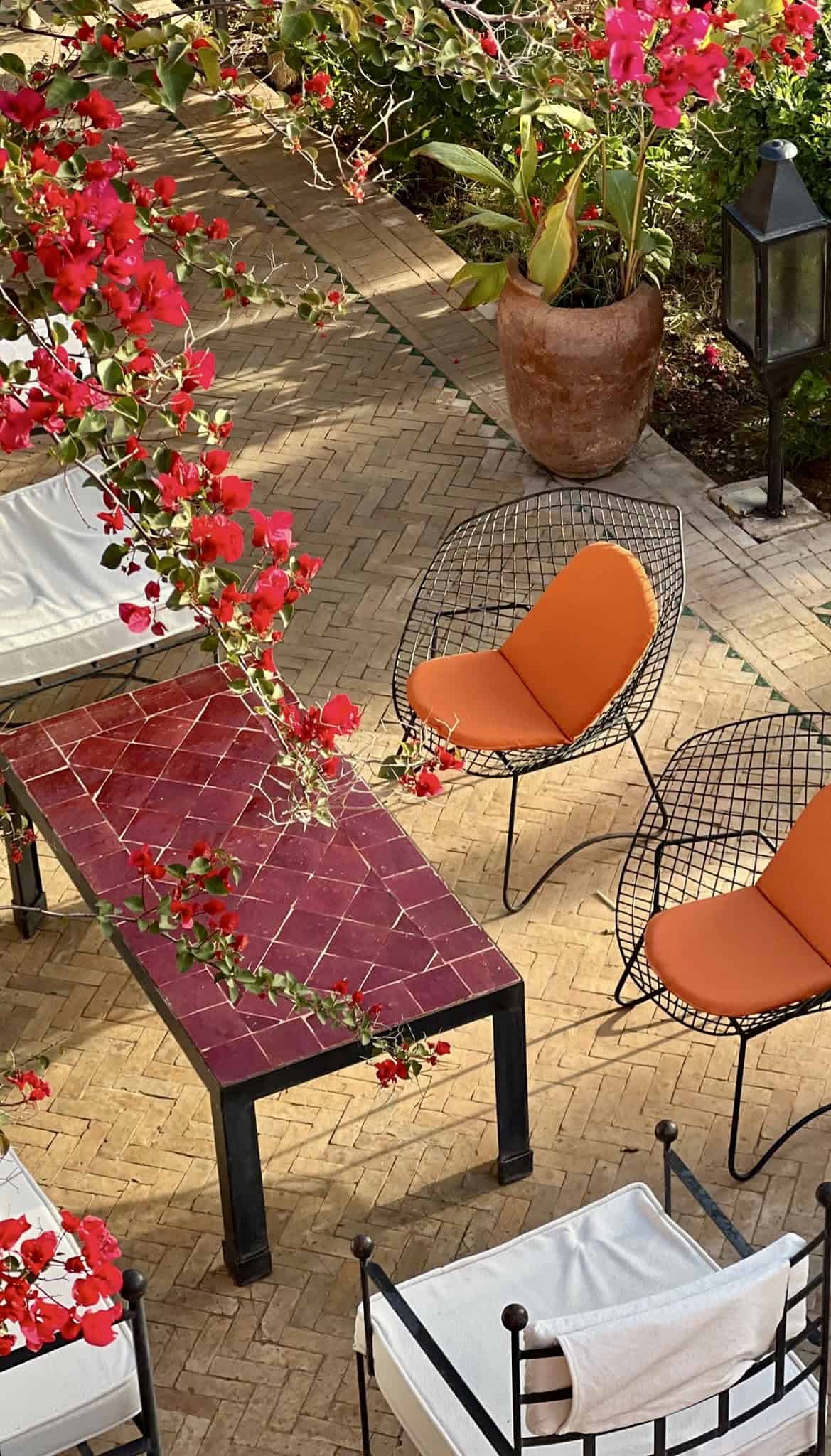 Zona relax con sedie arancioni, tavolo e piante colorate.