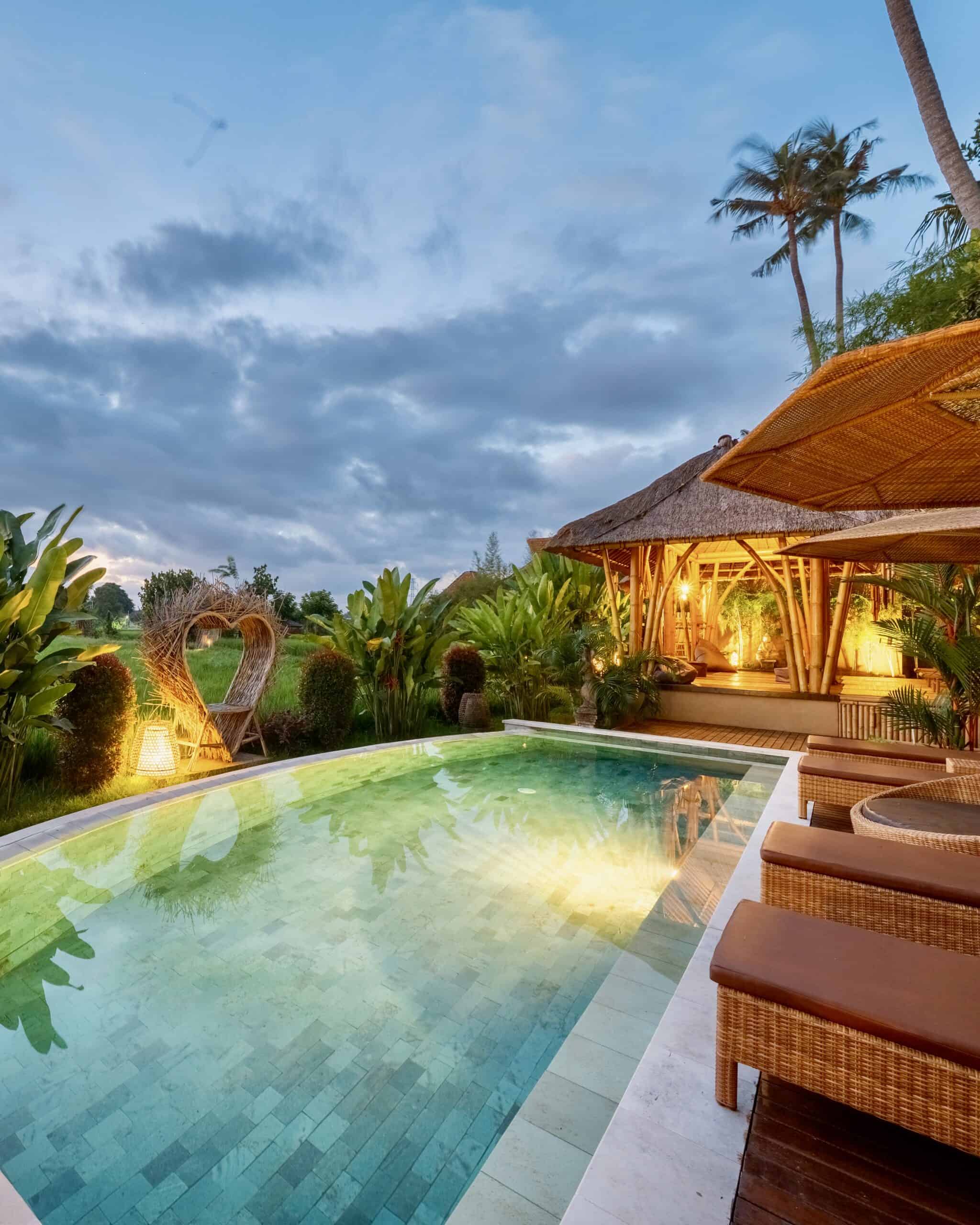Piscina in un resort tropicale con area relax e vegetazione rigogliosa.