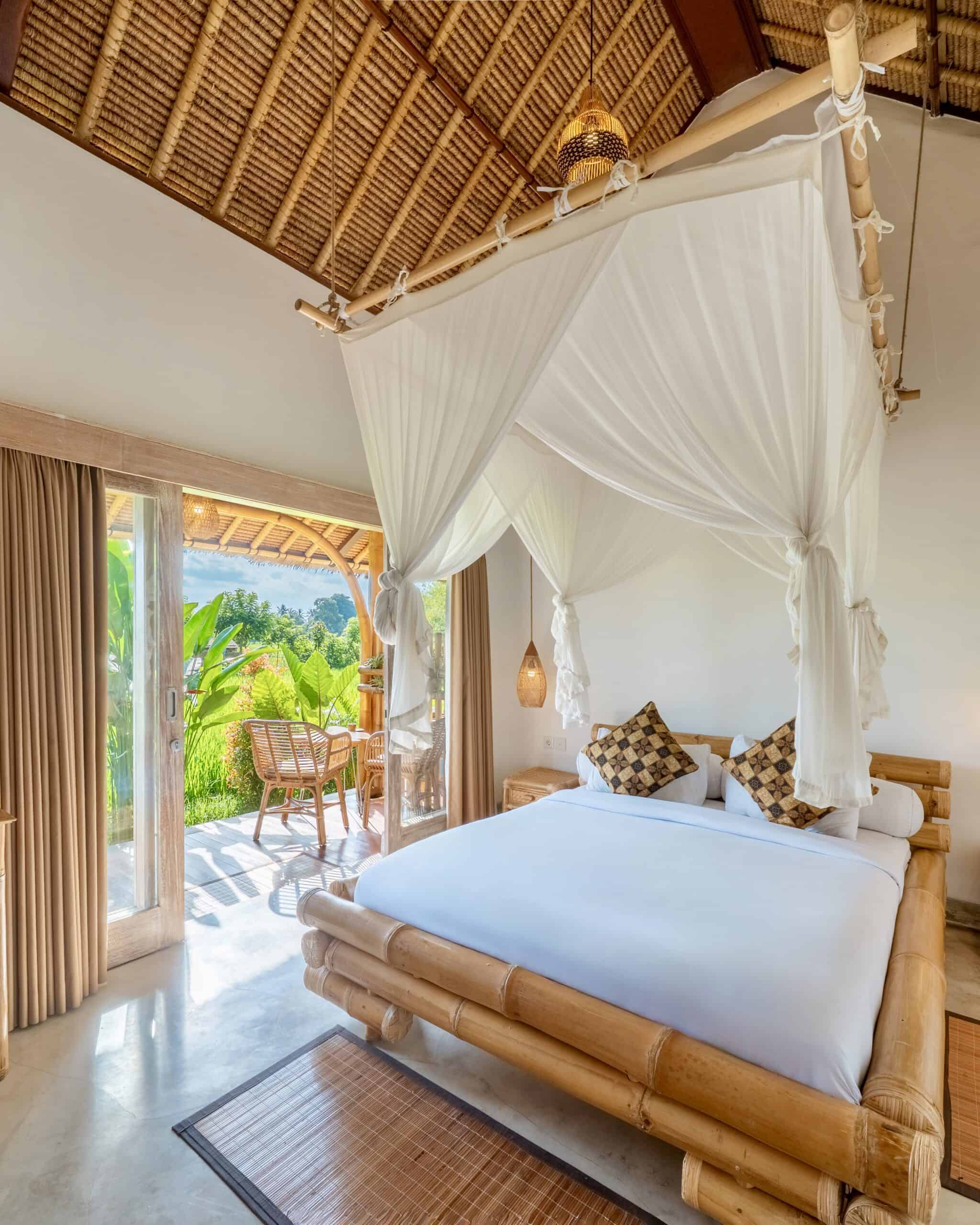 Camera da letto con zanzariera in stile tropicale, vista su giardino verde.