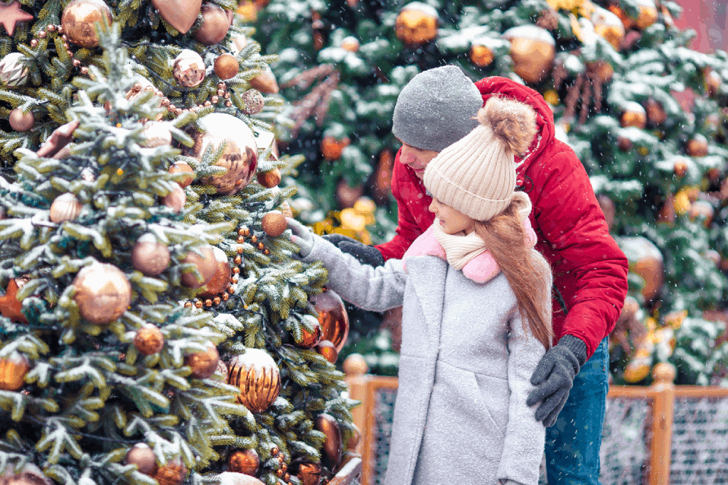Découvrir les marchés de Noël de Milan père et fille profitant de la magie de noël en observant les décorations d'un arbre de noël sous la neige