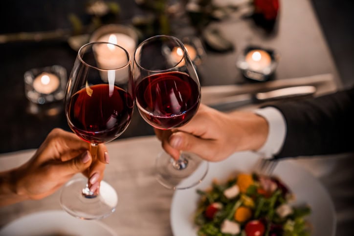 où aller pour un séjour à la saint-valentin ? couple qui trinque avec 2 verres de vin rouge.