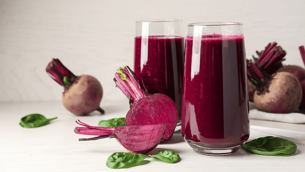 deux verres de smoothies betterave sur fond blanc, avec des betteraves dispersées autour