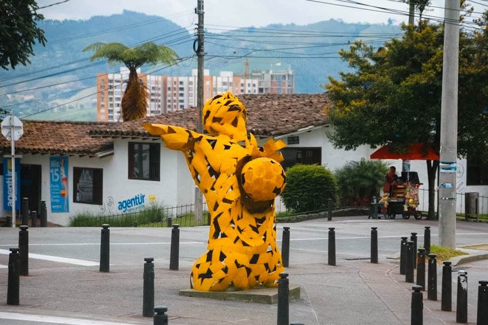A yellow sculpture of a torso with a head leaning back and a soccer ball in the middle of their chest.