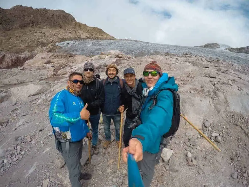 A group of hikers stands in front of a glacier on a guided hike in Los Nevados National Natural Park.