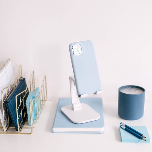A collection of blue stationery and tools on a desk with a mac computer. This desk is in use by someone using our daily journal prompts for teens