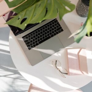 A laptop, some plants and a journal on a coffee table, ready for the user to do some positive thinking exercises