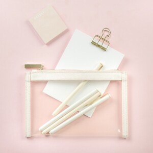 A picture of a note pad and pencil case on a pink background, ready to be used to explore the science of positive journaling
