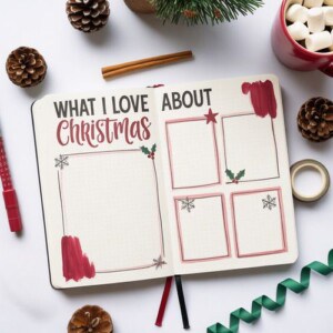 An open journal with the heading “what i love about christmas” sits among festive decorations, pinecones, blank frames for writing, and a cup of marshmallows—perfect inspiration for your christmas journaling ideas.