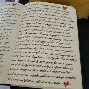 An open diary with handwritten cursive text in black ink fills both pages, perfect for mood and emotion journaling. Each page features a small red heart sketch at the top, with another red heart at the bottom right corner.