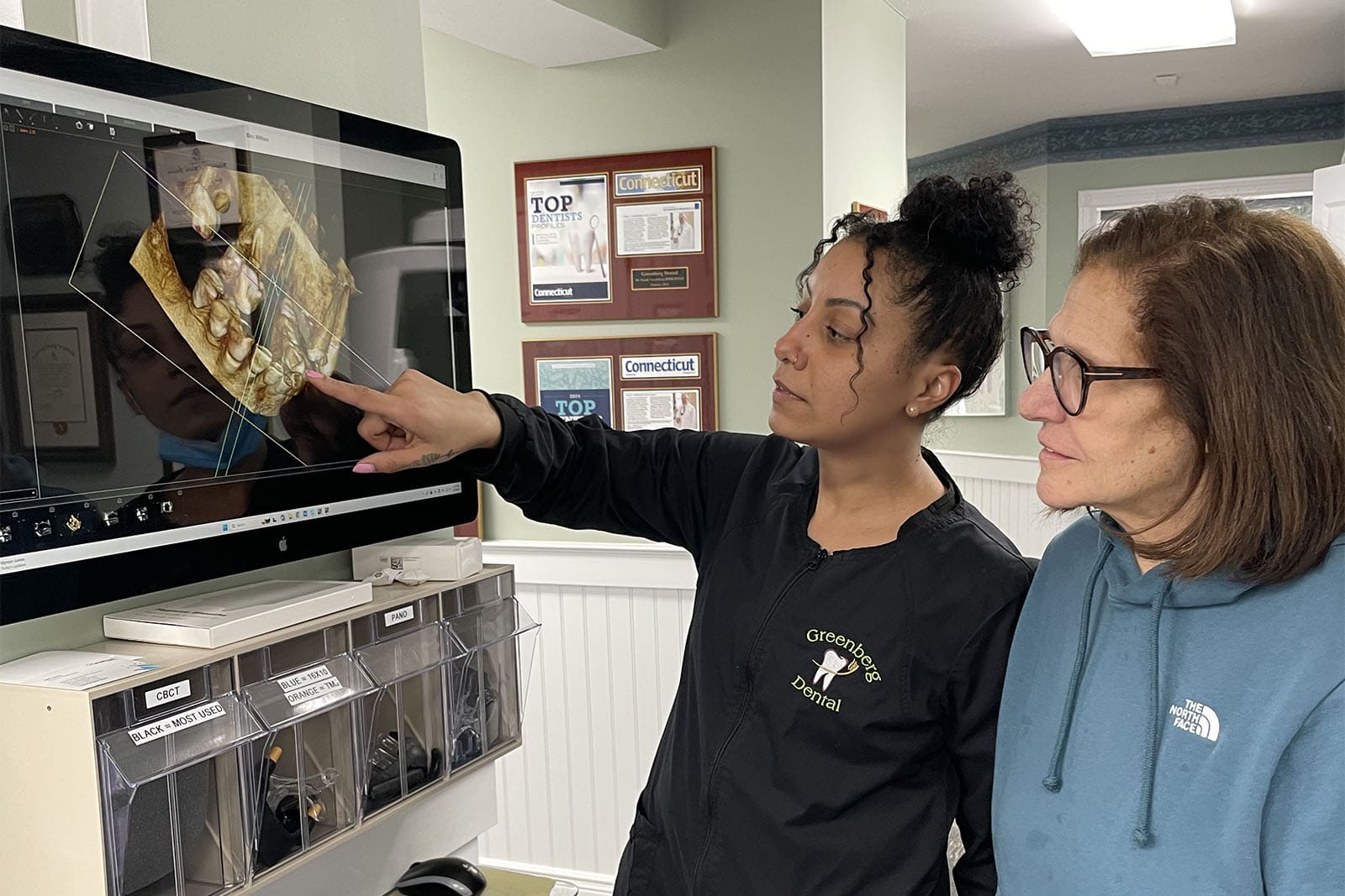 A dental assistant shows a patient a 3D teeth model