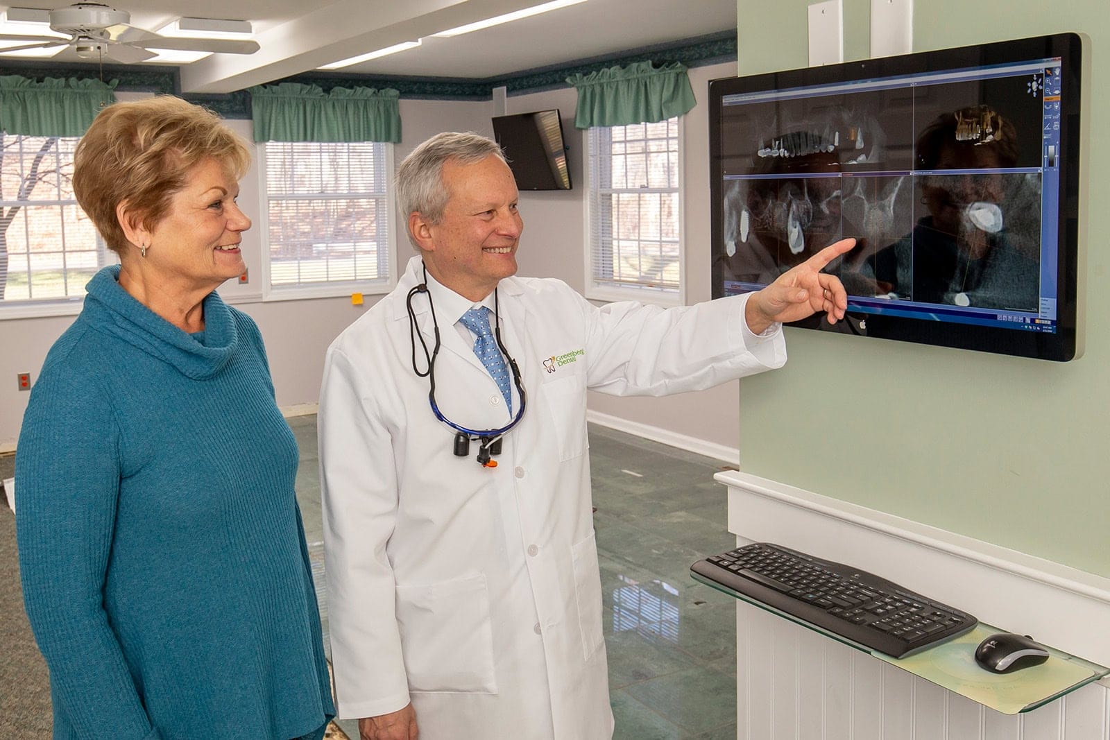 Dr. Randy Greenberg shows a patient a 3D teeth X-ray on a screen