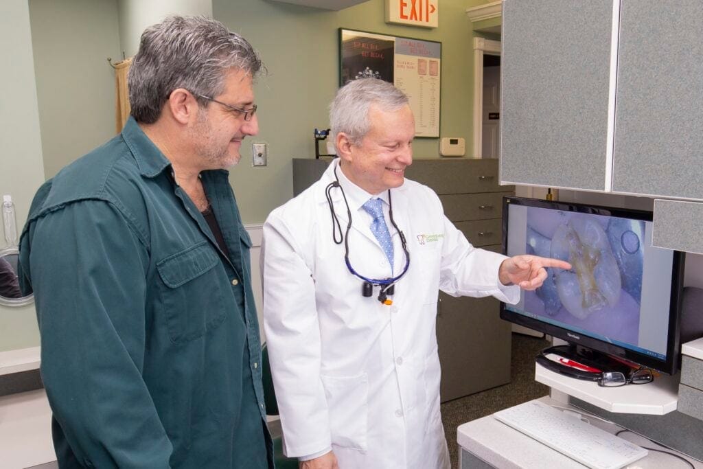 Dr. Randy Greenberg shows a patient a tooth on a screen