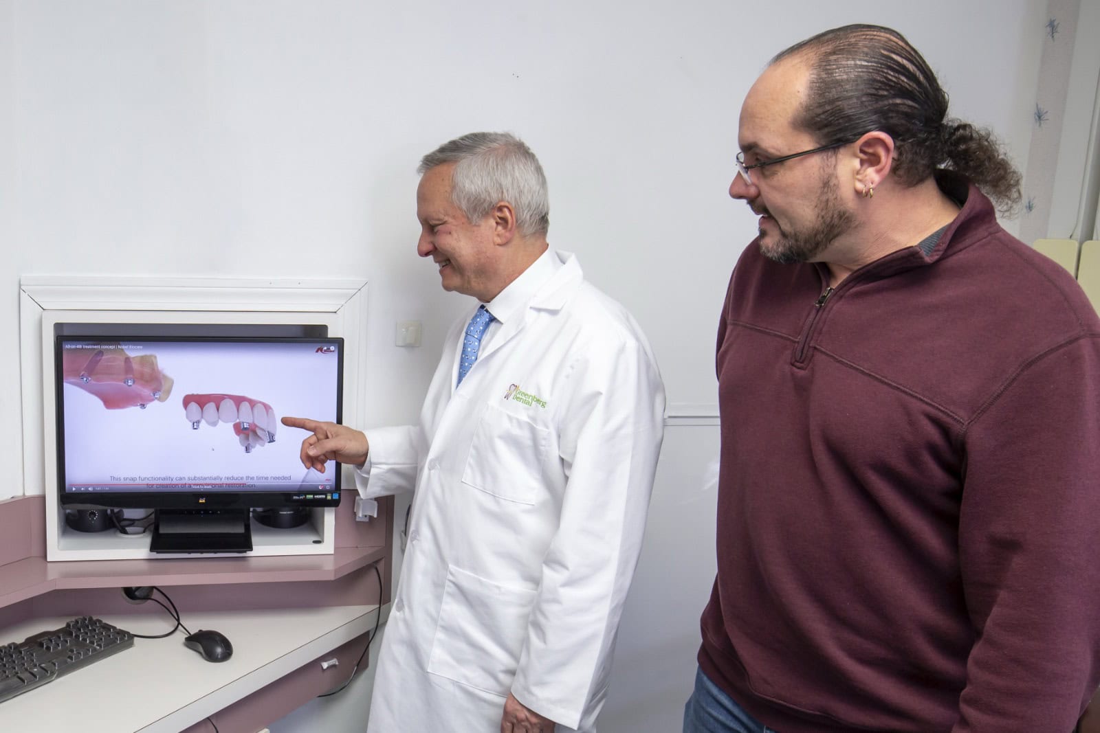 Dr. Randy Greenberg shows a patient a snap-in denture procedure