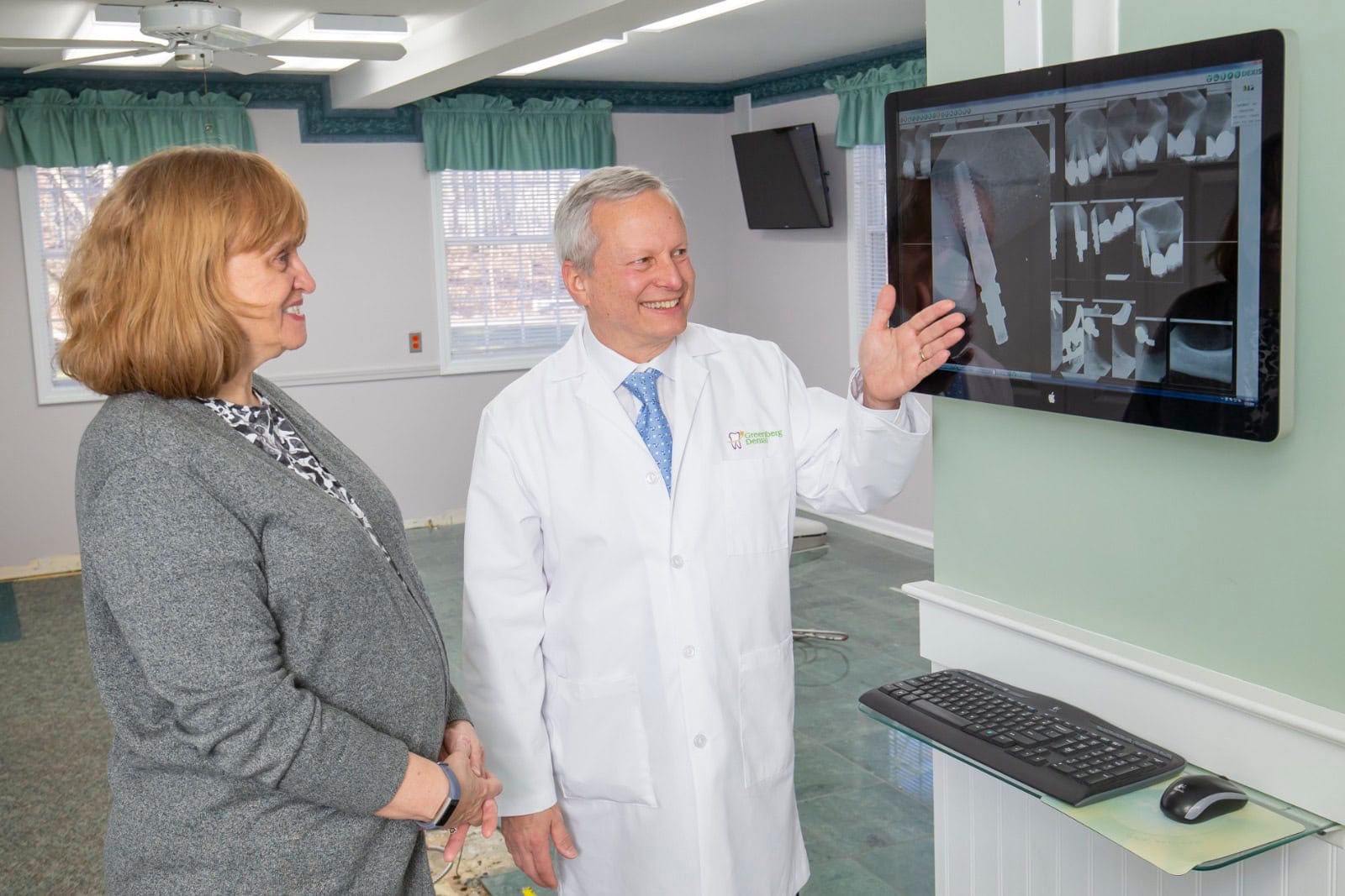 Dr. Randy Greenberg shows a patient an implant x-ray on a screen