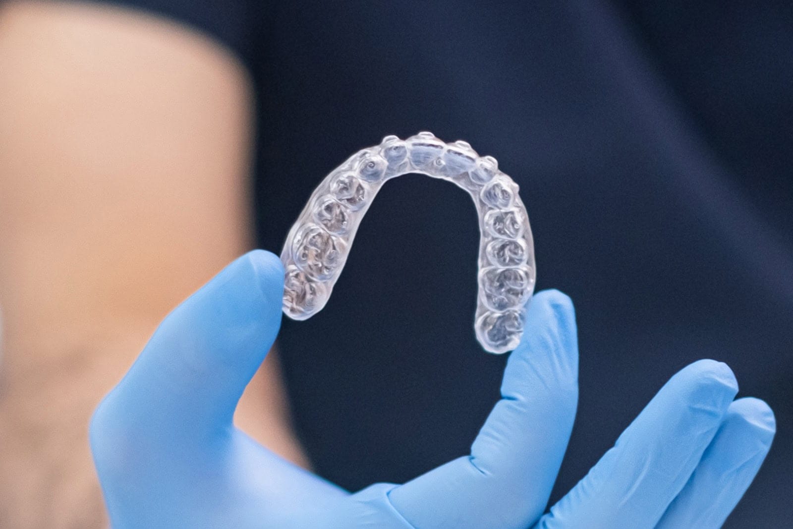Orthodontist in rubber gloves holding transparent aligners for correction of dentition