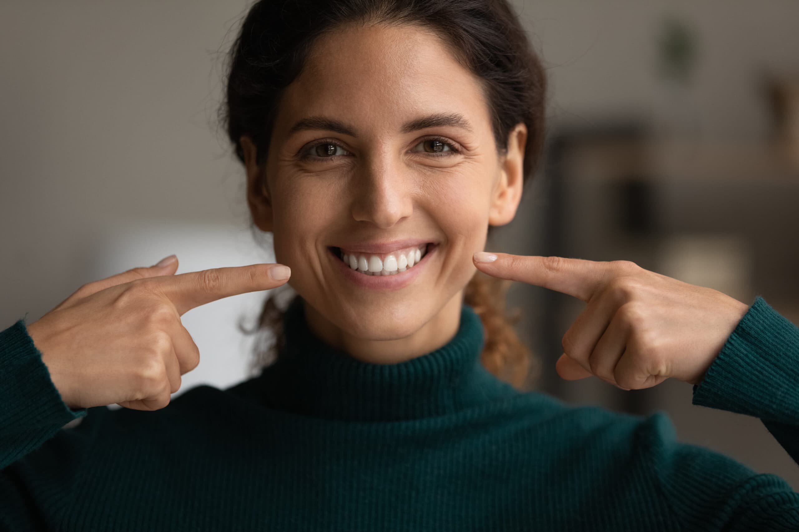 Smiling woman pointing at her smile.
