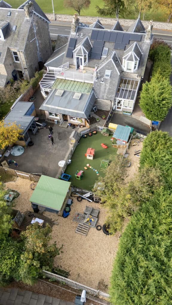 Bright aerial view of Thrive Childcare's outdoor play area, featuring colourful toys, sandbox, and adventure zone, emphasising safe and engaging childcare environments in a welcoming community setting.