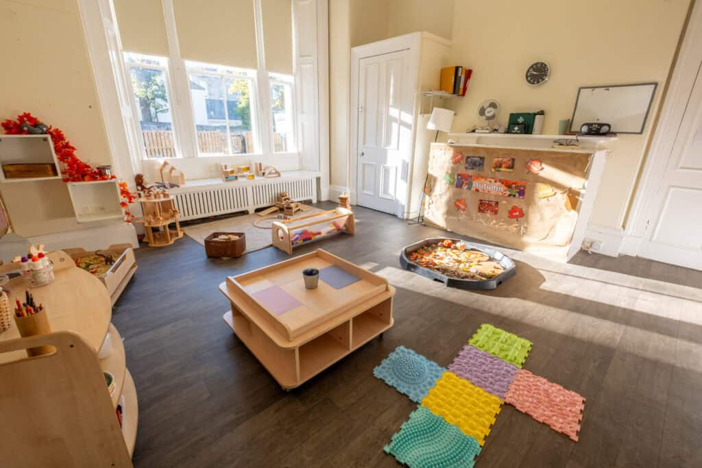 Bright, inviting early childhood learning and playroom with large windows, colourful sensory mats, and educational toys, ideal for fostering creativity and development at Thrive Childcare.
